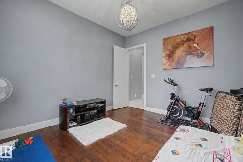 Hardwood flooring throughout featuring white baseboards, a contemporary light fixture, and a white interior door - 3036 59 Avenue, Rural Leduc County, AB 