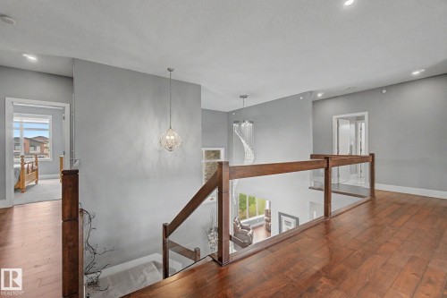 Upper level landing featuring wood-finish flooring, recessed lighting, and a glass panel railing with wood newel posts - 3036 59 Avenue, Rural Leduc County, AB 