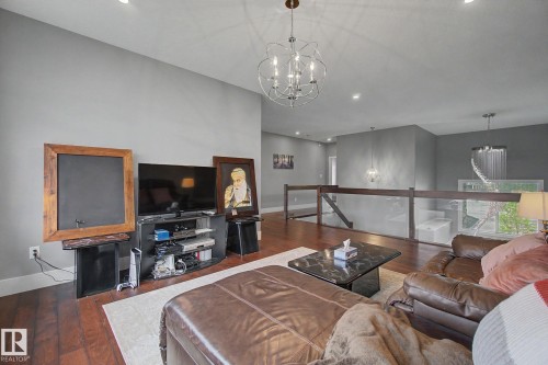 Spacious living area featuring wood-finish flooring, recessed lighting, and a modern chandelier - 3036 59 Avenue, Rural Leduc County, AB 