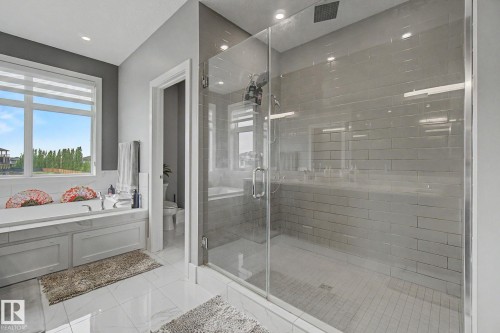 Spacious bathroom featuring a glass-enclosed shower with subway tile, a built-in soaking tub, large window, and white tile flooring - 3036 59 Avenue, Rural Leduc County, AB 