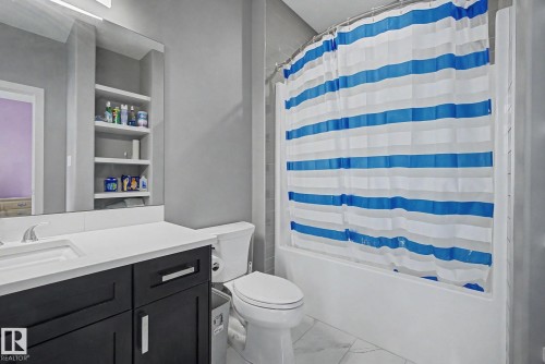 Bathroom with a white bathtub, white vanity countertop, dark wood-finish vanity cabinetry, built-in shelving, and white tile flooring - 3036 59 Avenue, Rural Leduc County, AB 