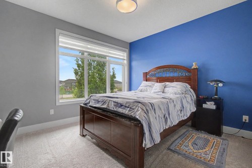 Bedroom featuring a large multi-pane window, light-toned carpet, and a ceiling-mounted light fixture - 3036 59 Avenue, Rural Leduc County, AB 