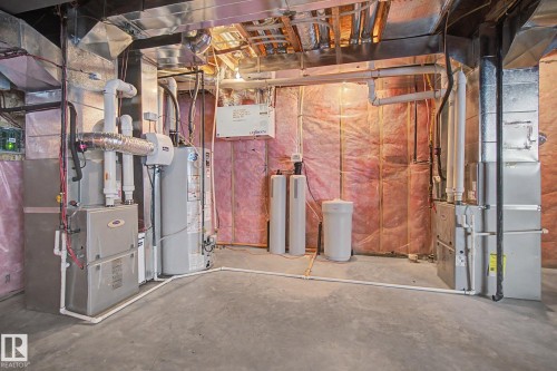 Basement utility area featuring two furnaces, a water heater, a water softener system, and exposed ductwork - 3036 59 Avenue, Rural Leduc County, AB 