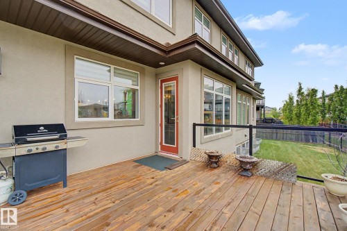 Spacious wood-finish deck with a glass and metal railing overlooking a fenced yard - 3036 59 Avenue, Rural Leduc County, AB 