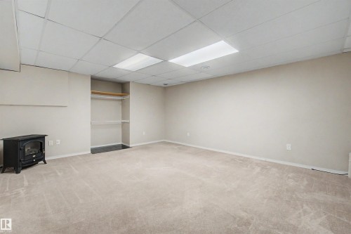 Spacious room featuring neutral carpeting, light-toned walls, and a drop ceiling with integrated lighting - 2068 45 Street, Edmonton, AB - Indoor Photo Showing Basement