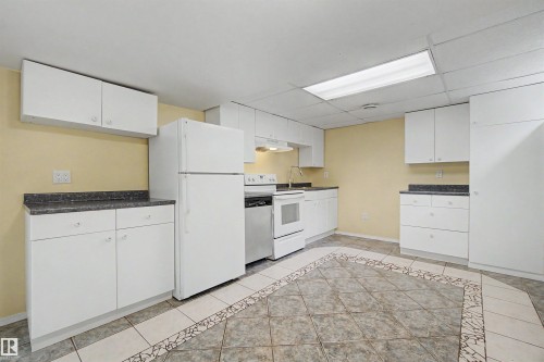 Kitchen featuring white cabinetry, dark speckled countertops, and integrated white appliances - 2068 45 Street, Edmonton, AB - Indoor Photo Showing Kitchen