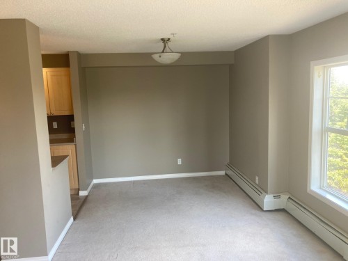 Carpeted living area with neutral wall tones and white baseboards - #206 616 Mcallister Lo Sw, Edmonton, AB - Indoor Photo Showing Other Room