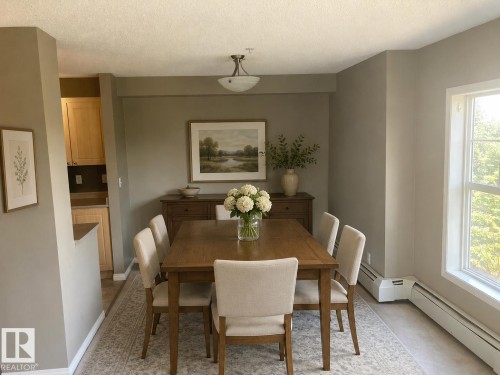 Dining area featuring neutral wall tones, a large window, white baseboard trim, and a ceiling-mounted light fixture - #206 616 Mcallister Lo Sw, Edmonton, AB - Indoor Photo Showing Dining Room