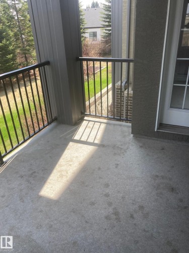 Concrete balcony featuring black metal railings and a glass-paneled exterior door - #206 616 Mcallister Lo Sw, Edmonton, AB - Outdoor With Balcony With Exterior