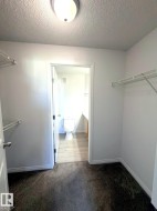 Carpeted closet space with wire shelving, offering direct access to a separate bathroom featuring wood-finish flooring and a toilet - 