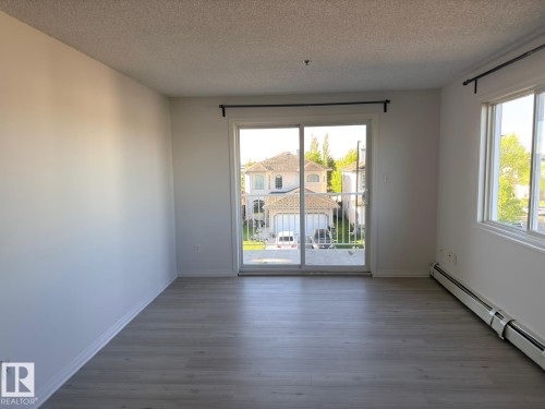 Spacious room featuring light wood-finish flooring, white baseboards, and neutral wall paint - 312 2305 35A Avenue, Edmonton, AB 