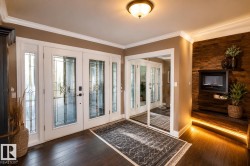 Entryway featuring double doors with decorative glass panels and sidelights, dark wood-finish flooring, and crown molding - 