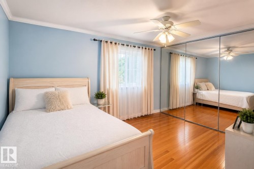 Bedroom featuring wood-finish flooring, a ceiling fan, crown molding, and mirrored closet doors - 58124 Secondary 881, Rural St. Paul County, AB - Indoor Photo Showing Bedroom