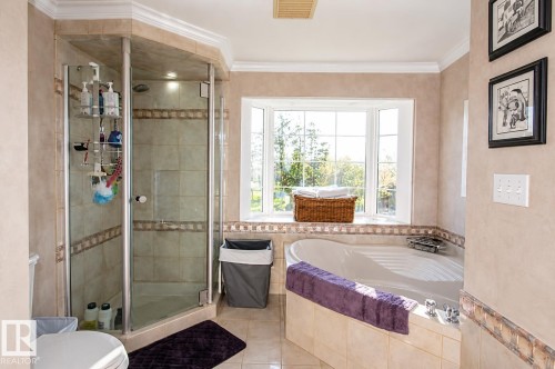 Tiled bathroom featuring a corner glass-enclosed shower, a built-in jetted tub, and a multi-pane bay window - 58124 Secondary 881, Rural St. Paul County, AB - Indoor Photo Showing Bathroom
