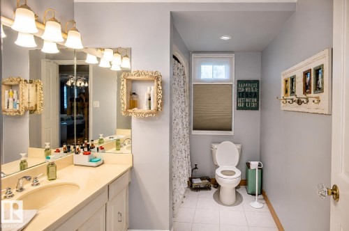 Bathroom featuring a single vanity with an integrated sink, a large mirror, and overhead vanity lighting - 58124 Secondary 881, Rural St. Paul County, AB - Indoor Photo Showing Bathroom