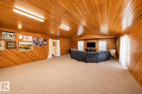 Spacious room featuring wood-paneled walls and ceiling, wall-to-wall carpeting, and multiple windows - 58124 Secondary 881, Rural St. Paul County, AB - Indoor Photo Showing Other Room