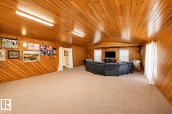 Spacious room featuring wood-paneled walls and ceiling, wall-to-wall carpeting, and multiple windows - 