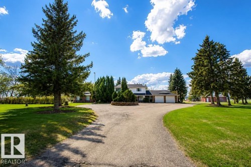 Spacious driveway encircling a landscaped island, leading to a white two-story residence with a three-car garage - 58124 Secondary 881, Rural St. Paul County, AB - Outdoor