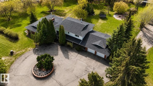 Spacious property featuring a large residence with a multi-car garage, expansive green lawn, mature trees, and a circular driveway with a central planted island - 58124 Secondary 881, Rural St. Paul County, AB - Outdoor With View