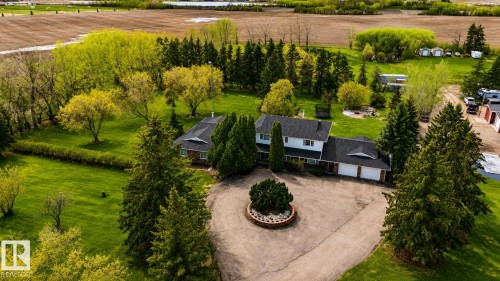 Expansive grounds featuring a two-story residence with attached multi-car garage, mature landscaping, circular driveway, and surrounding agricultural fields - 58124 Secondary 881, Rural St. Paul County, AB - Outdoor
