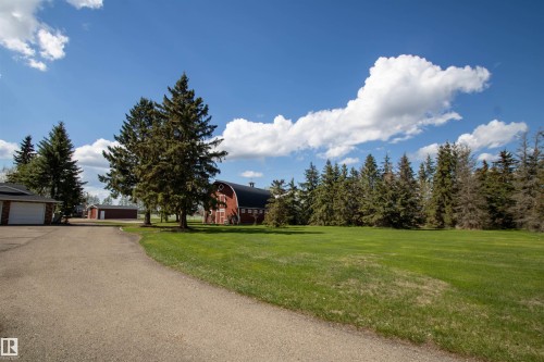 Expansive green lawn with mature evergreen trees and a paved driveway - 58124 Secondary 881, Rural St. Paul County, AB - Outdoor
