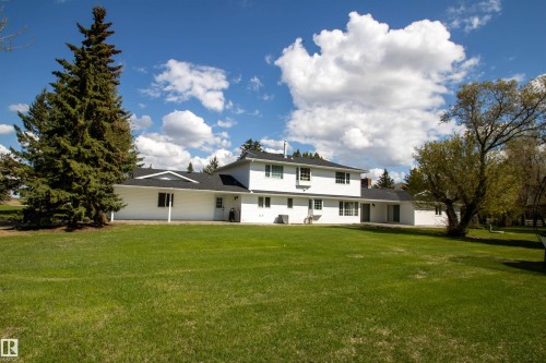 Expansive green lawn bordering a white-sided residence with multiple windows and mature trees - 58124 Secondary 881, Rural St. Paul County, AB - Outdoor