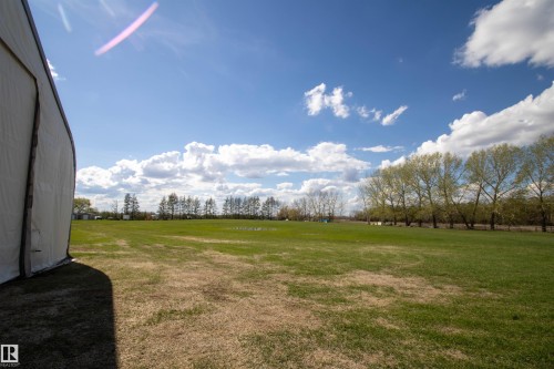 Expansive open field with green grass, bordered by a line of mature trees - 58124 Secondary 881, Rural St. Paul County, AB - Outdoor With View