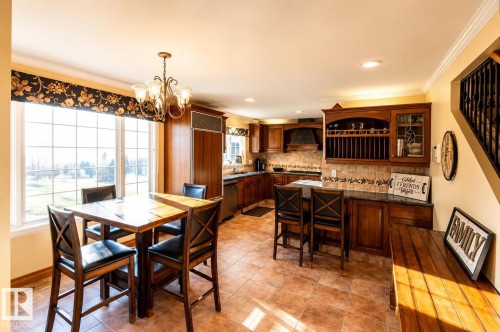 Kitchen and dining area featuring warm-toned floor tiles and extensive wood cabinetry - 58124 Secondary 881, Rural St. Paul County, AB - Indoor Photo Showing Dining Room