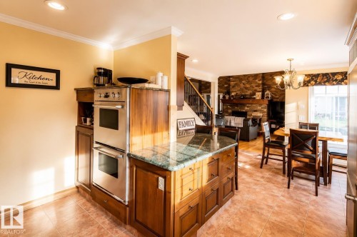Kitchen island with a polished stone countertop and rich wood-finish cabinetry - 58124 Secondary 881, Rural St. Paul County, AB - Indoor