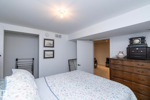 Recessed open closet space and white walls characterize this room, featuring a simple ceiling-mounted light fixture and a standard interior door - 7719 86 Avenue, Edmonton, AB 