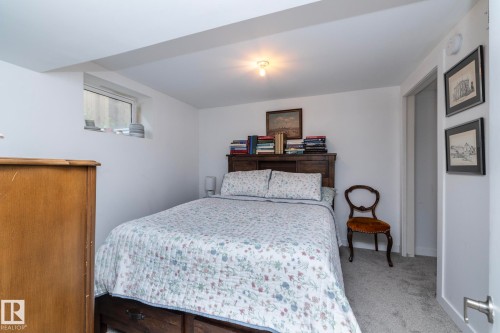 Bedroom featuring a built-in wood headboard with shelving, white painted walls, a horizontal window, and gray carpet flooring - 7719 86 Avenue, Edmonton, AB 