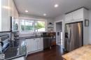 Kitchen featuring white cabinetry, dark stone countertops, stainless steel appliances, and wood-finish flooring - 7719 86 Avenue, Edmonton, AB 