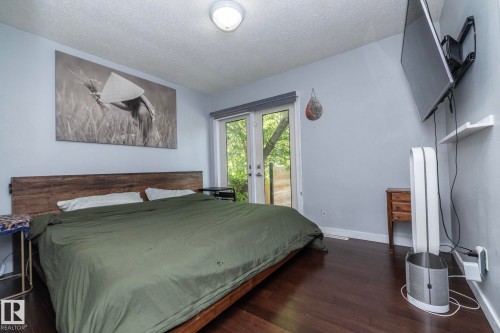 Hardwood-finish flooring, a wood headboard, and light blue walls define this space - 7719 86 Avenue, Edmonton, AB 