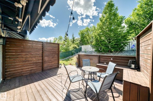 Expansive outdoor deck featuring wood-finish flooring, integrated wood fencing, and a built-in wood bench - 13 Orchid Place, St. Albert, AB 