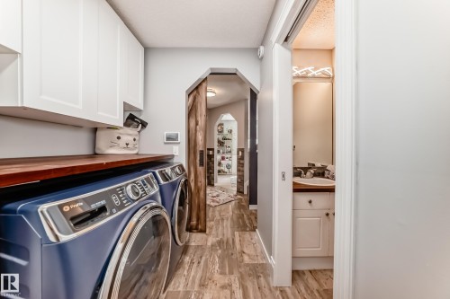 Dedicated laundry area featuring white upper cabinetry and a wood-finish countertop - 13 Orchid Place, St. Albert, AB 