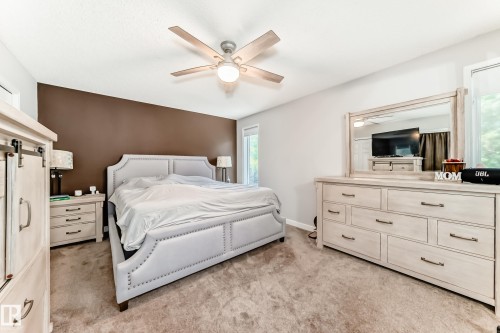 Bedroom featuring a light brown carpet, white walls with a contrasting accent wall, and a ceiling fan with light fixture - 13 Orchid Place, St. Albert, AB 