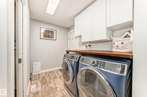 Dedicated laundry area featuring wood-finish flooring, white cabinetry, and a wood-finish countertop - 13 Orchid Place, St. Albert, AB 