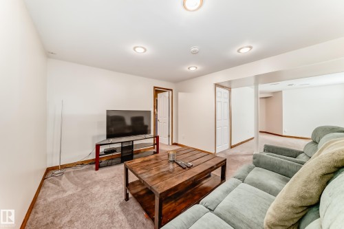 Carpeted finished lower level featuring recessed lighting, a built-in support column, and a paneled white door - 13 Orchid Place, St. Albert, AB 