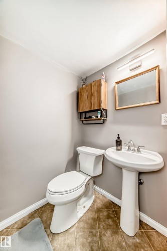 Pedestal sink with chrome faucet and framed mirror, featuring a wall-mounted light fixture - 13 Orchid Place, St. Albert, AB 