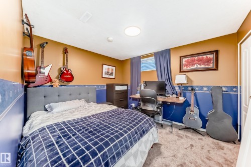 Carpeted bedroom with a built-in wall desk, window with blinds, and white interior door - 13 Orchid Place, St. Albert, AB 