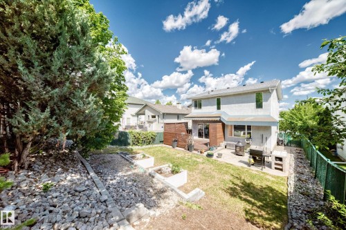 Rear exterior featuring a multi-level patio with stone pavers, a wooden deck, and a retractable awning - 13 Orchid Place, St. Albert, AB 