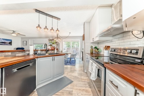 Kitchen featuring light-toned cabinetry, wood-finish countertops, stainless steel appliances, and subway tile backsplash - 13 Orchid Place, St. Albert, AB 