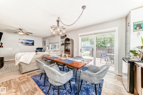 Open-concept dining area featuring wood-finish flooring, a contemporary chandelier, and direct access to the outdoor space via sliding glass doors - 13 Orchid Place, St. Albert, AB 