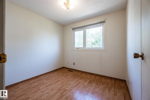 Room featuring a window with a blind, wood-finish flooring, white walls, and a ceiling light fixture - 20 11115 27 Avenue, Edmonton, AB 
