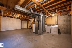Full unfinished basement featuring exposed wood joists, concrete walls, concrete flooring, and a dedicated laundry area with appliances - 