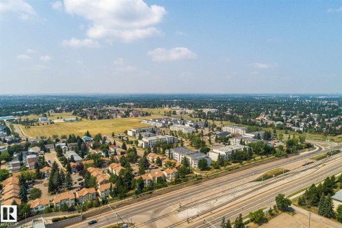 Expansive aerial perspective showcasing a developed urban landscape with diverse residential structures, abundant mature trees, a multi-lane highway, and open green spaces - 20 11115 27 Avenue, Edmonton, AB 
