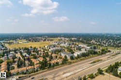 Expansive aerial perspective showcasing a developed urban landscape with diverse residential structures, abundant mature trees, a multi-lane highway, and open green spaces - 