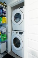 Dedicated laundry alcove featuring a stacked washer and dryer unit - 