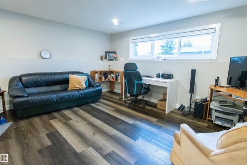 Spacious room featuring multi-tone wood-finish flooring, a contemporary window, recessed lighting, and a neutral color palette - 4004 88 Street, Edmonton, AB 