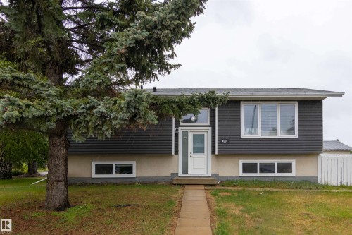Split-level residence featuring a white entry door with frosted glass, dark horizontal siding, and a light-colored foundation - 4004 88 Street, Edmonton, AB 